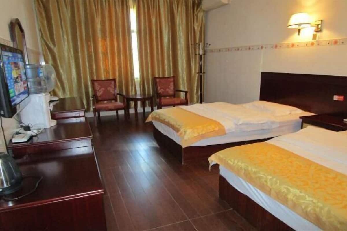 Ein Hotelzimmer mit zwei Betten, einem Schreibtisch mit Telefon, einem Wasserspender und einem Stuhl.