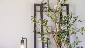 A cozy room with a wooden table, a potted olive tree, a floor lamp, and a bookshelf. - Spacious 5B2B home 5 min to airport with AC, Game Room, Sleeps 16 (SeaTac)