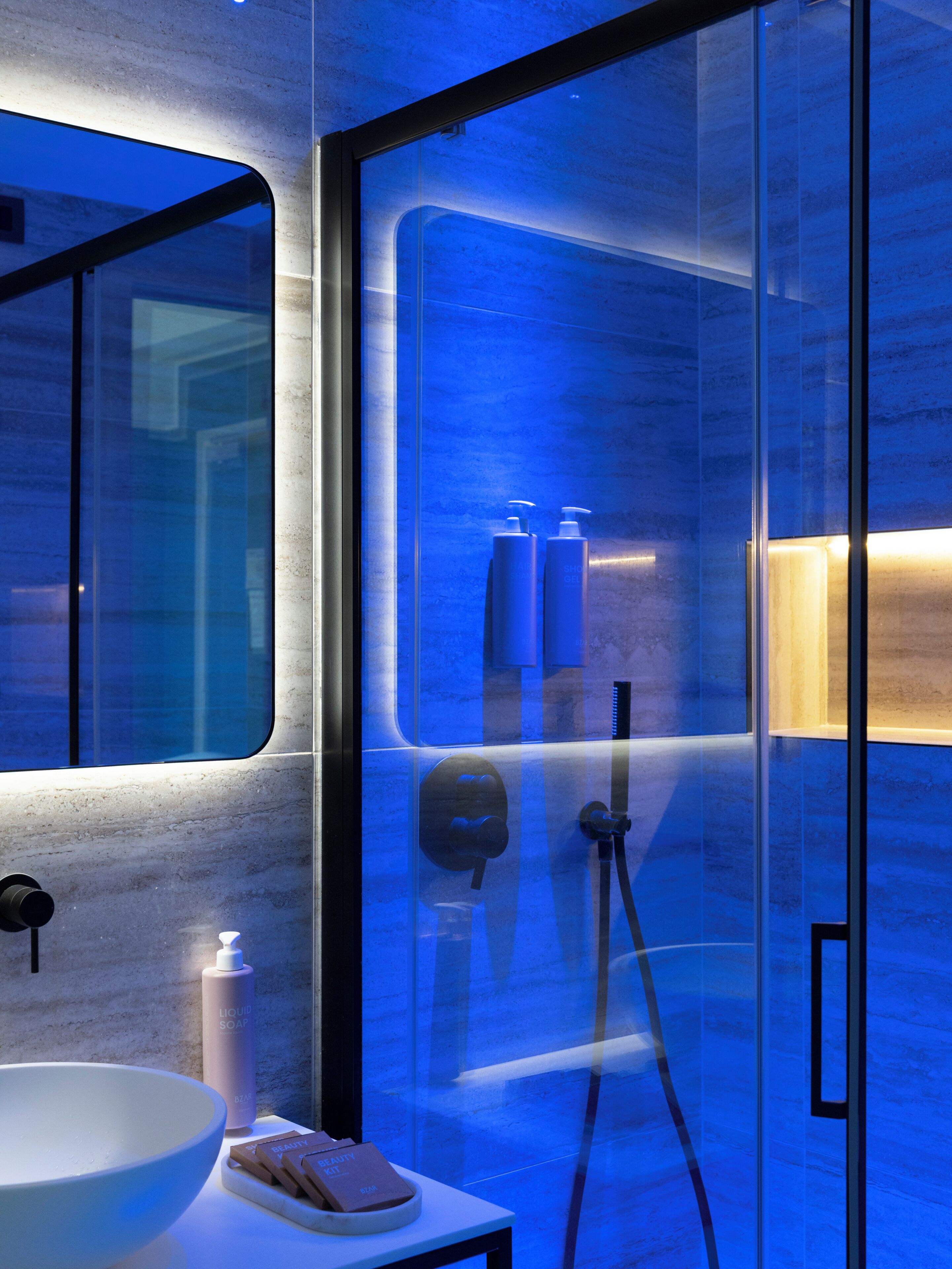 Un bagno moderno con cabina doccia in vetro, lavabo bianco e articoli da toilette.