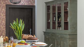 A dining area with a table set for a meal, a cabinet with glass doors, and a hanging light fixture.