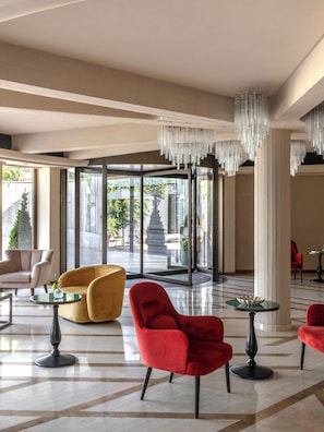 Un hall d’entrée spacieux, doté de meubles modernes, d’une grande porte vitrée donnant sur l’extérieur et d’un lustre décoratif.