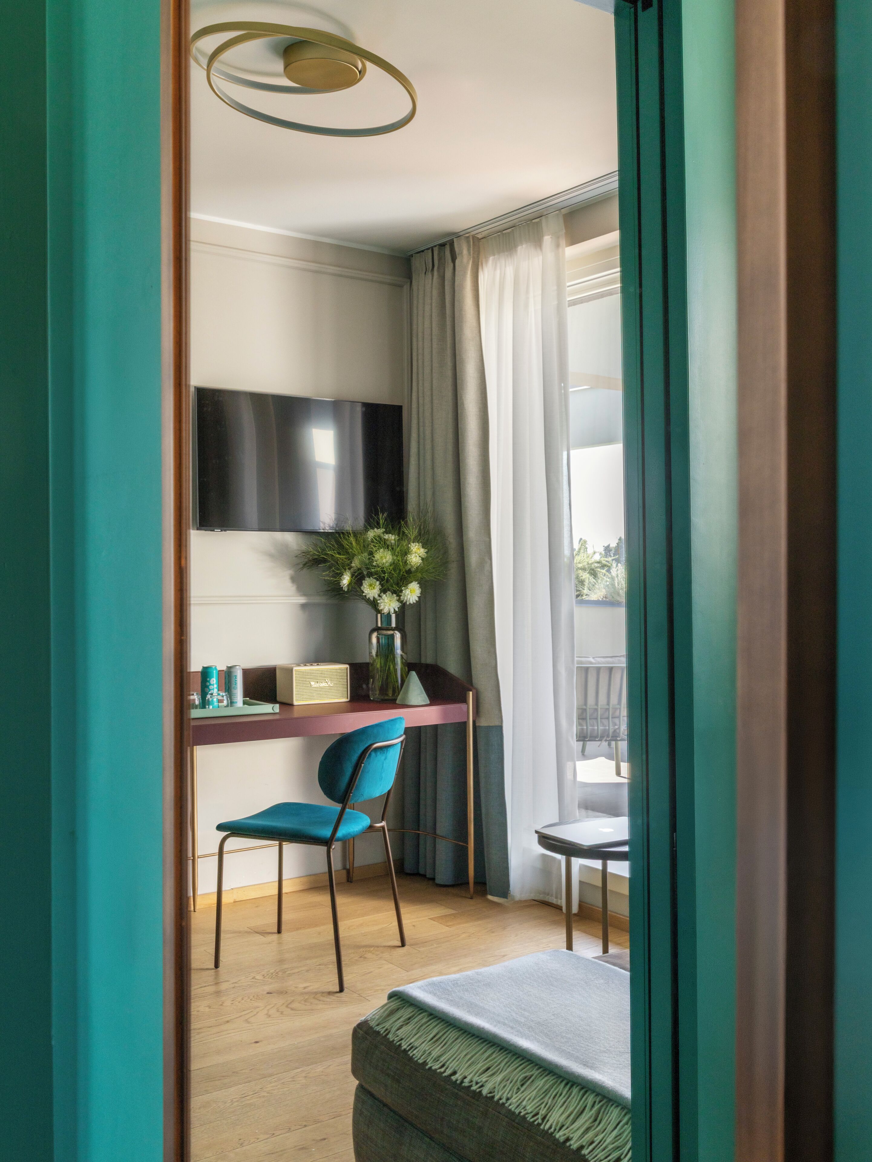Une pièce comprenant un bureau, une chaise, un téléviseur et une fenêtre avec des rideaux.