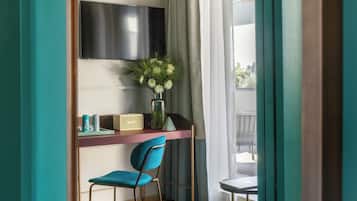 Une pièce comprenant un bureau, une chaise, un téléviseur et une fenêtre avec des rideaux.