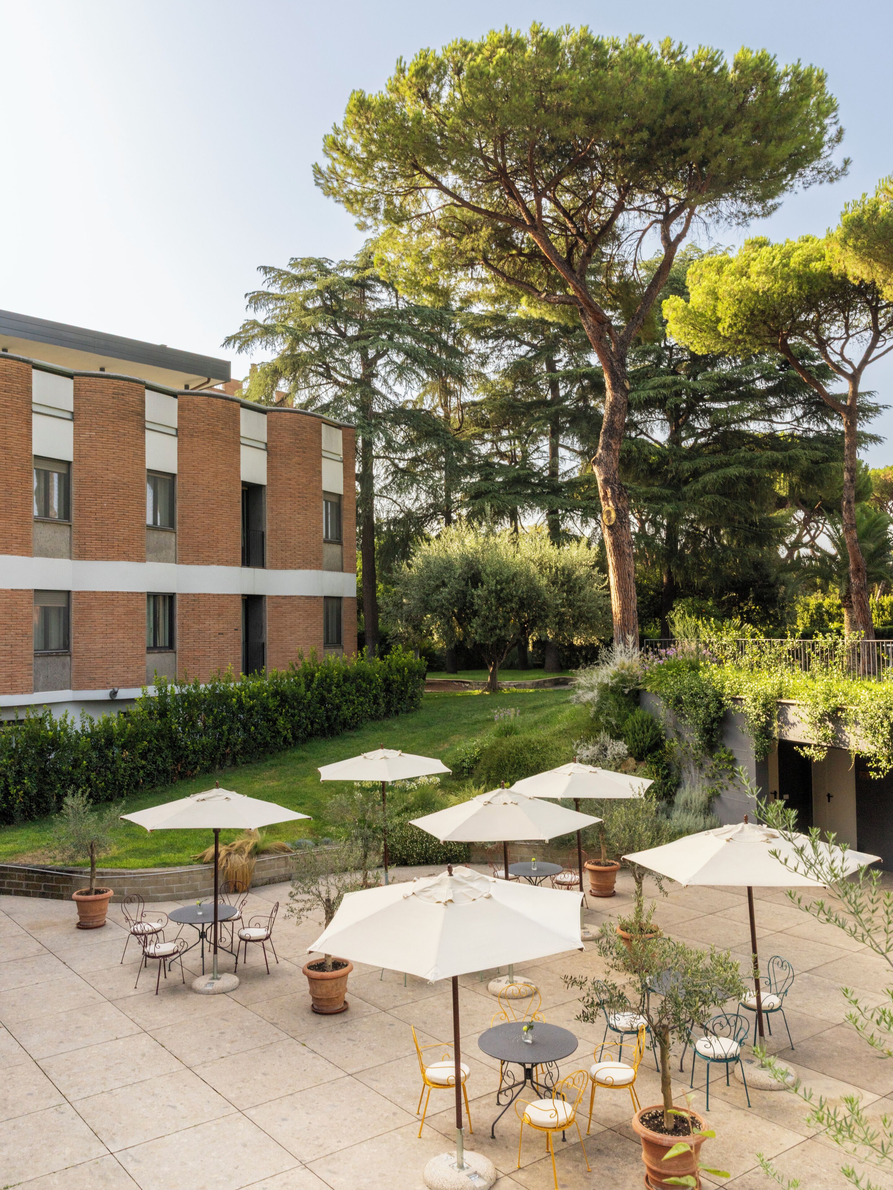 Un'area patio all'aperto con tavoli e sedie, immersa nel verde e alberi.