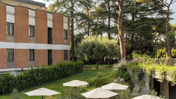 Un'area patio all'aperto con tavoli e sedie, immersa nel verde e alberi.