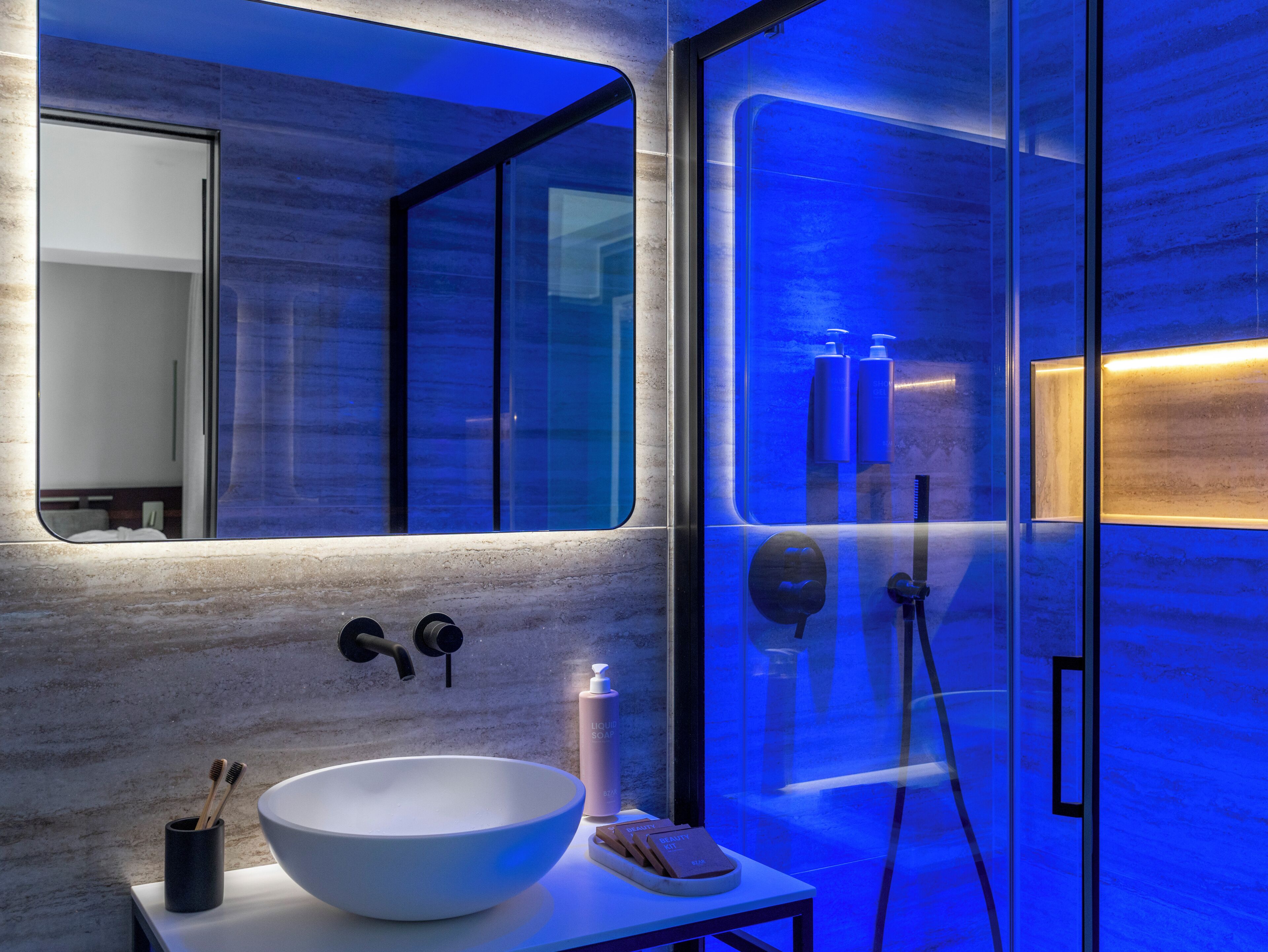 Un baño moderno con un lavabo blanco grande, un espejo y una cabina de ducha con paredes de vidrio.