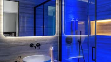 Un baño moderno con un lavabo blanco grande, un espejo y una cabina de ducha con paredes de vidrio.