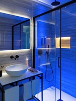 A modern bathroom with a large white sink, a mirror, and a glass-enclosed shower area.