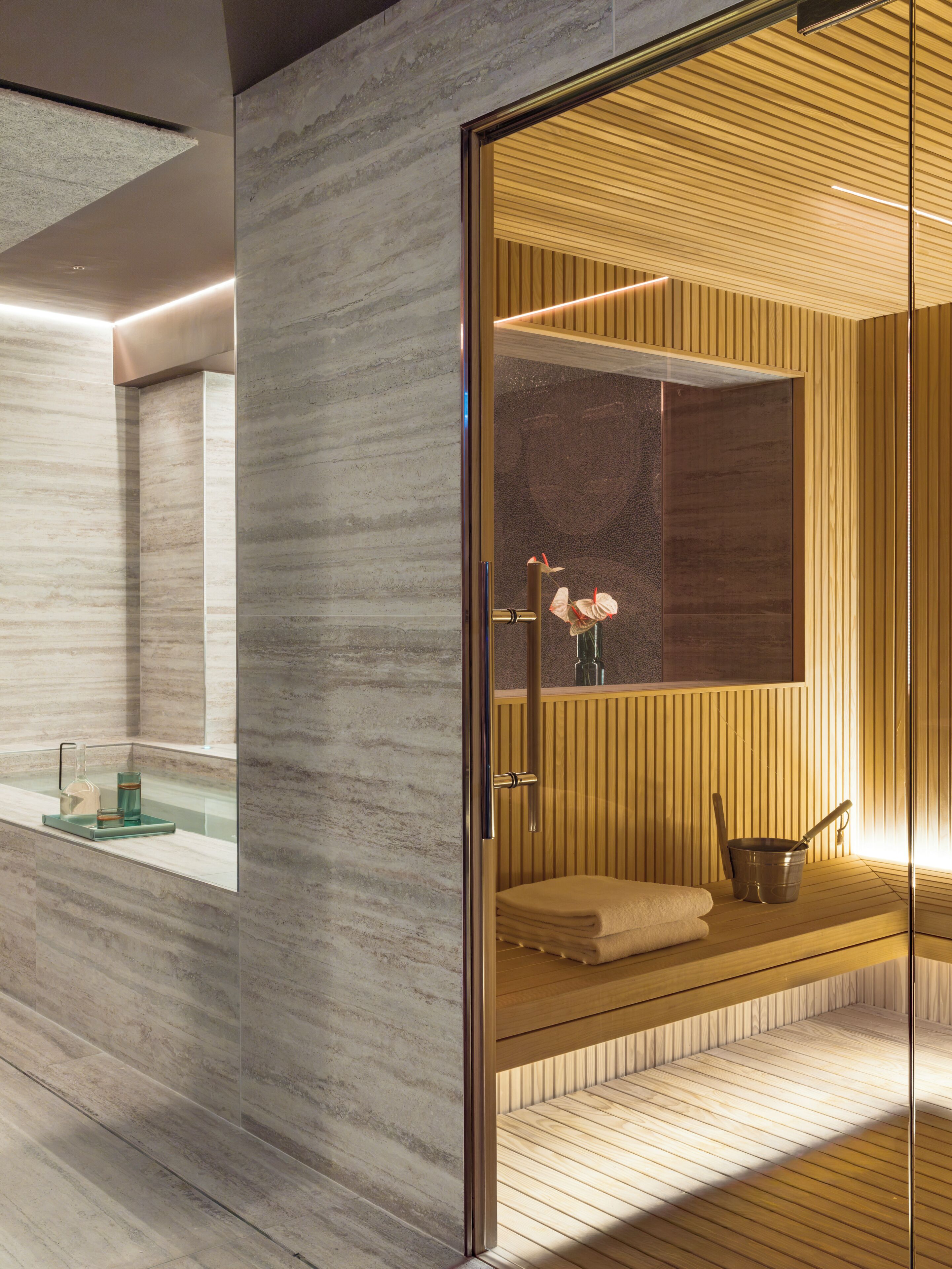 Ein modernes Badezimmer mit Glasabtrennung, Holzboden und Handtuchhalter.