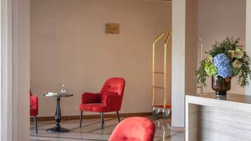 Un vestíbulo moderno con sillas rojas, un mostrador de recepción y una lámpara colgante decorativa.