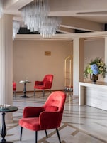 En moderne lobby med røde stole, en reception og en dekorativ hængende lampe.