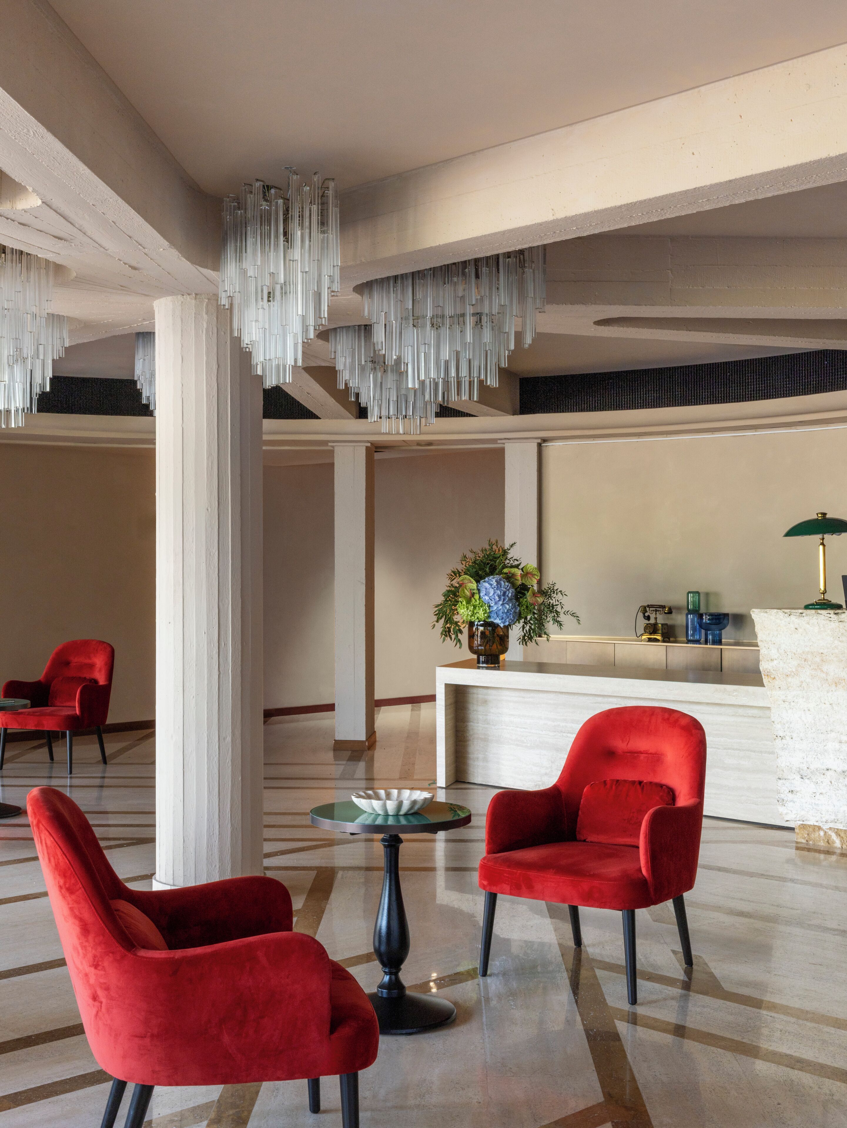 A lobby with red chairs, a reception desk, and a hanging light fixture.