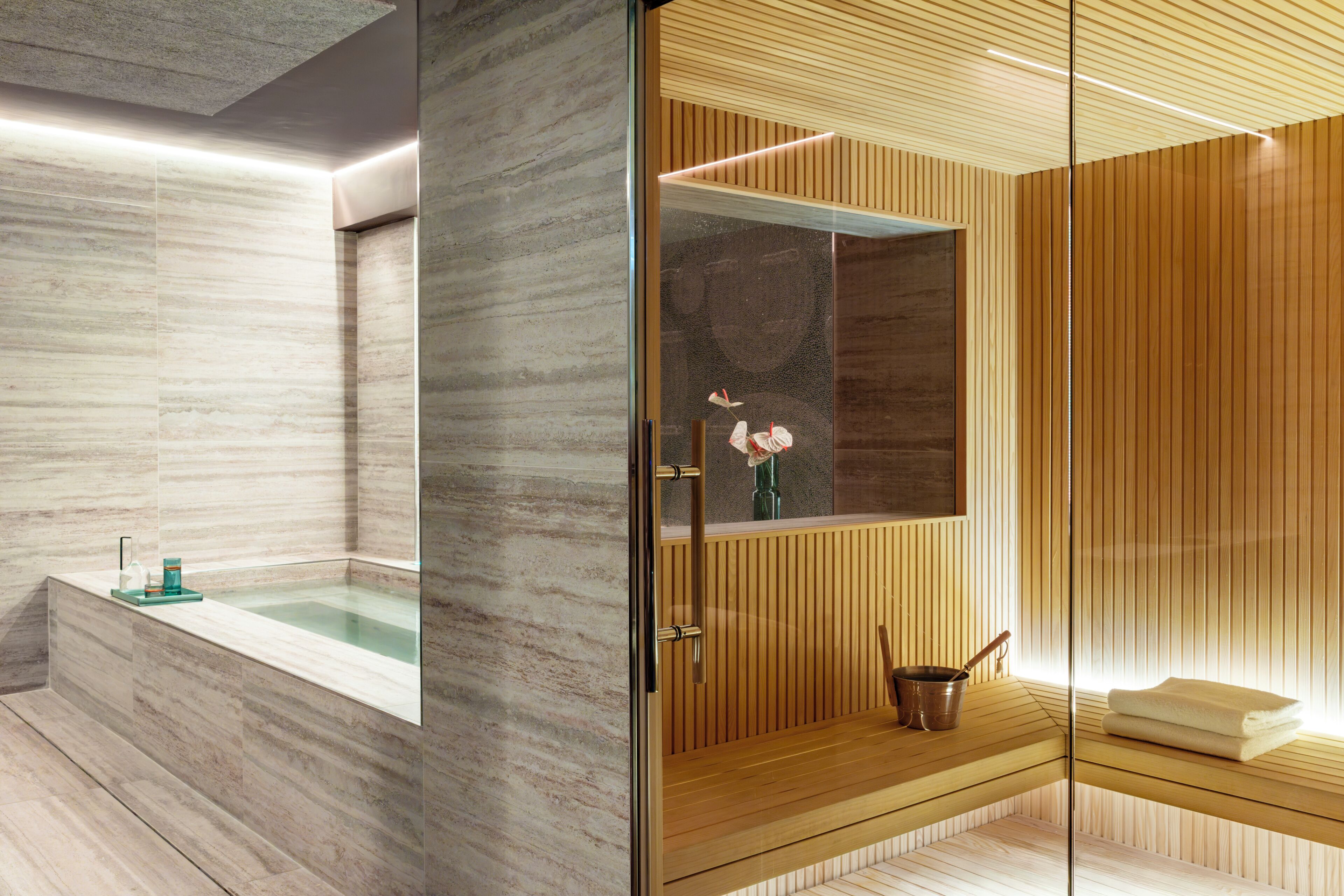Un bagno moderno con una vasca da bagno in marmo, un mobile vanitario in legno e un box doccia in vetro.
