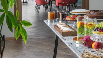 Ein Essbereich mit einem Tisch, gedeckt für das Frühstück, einschließlich Brot, Obst und Gebäck.
