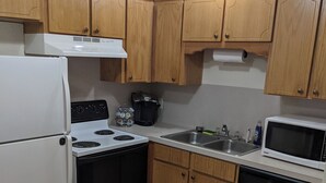 Une cuisine compacte avec des meubles en bois, un réfrigérateur blanc, une cuisinière, un four à micro-ondes et un lave-vaisselle.