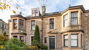 A traditional stone building with a symmetrical facade, multiple windows, and a central entrance. - Stunning 5 Bedroom Large Apartment With Parking (Edinburgh)