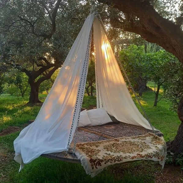 Una hamaca colgada bajo un árbol con una manta estampada.