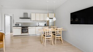 Een moderne keuken met witte kastjes, een eettafel met stoelen en een groot raam.