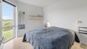 Een moderne slaapkamer met een groot bed, een raam en uitzicht op groen.