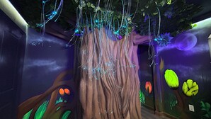 A room with a tree-themed wall mural, a wooden floor, and a ceiling with hanging lights. - Storey Lake Amazing Water view, Game Room, Movie Room and Theme Rooms (Kissimmee)