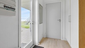 Ein Flur mit einer weißen Tür, einem kleinen Fenster und Holzdielen.
