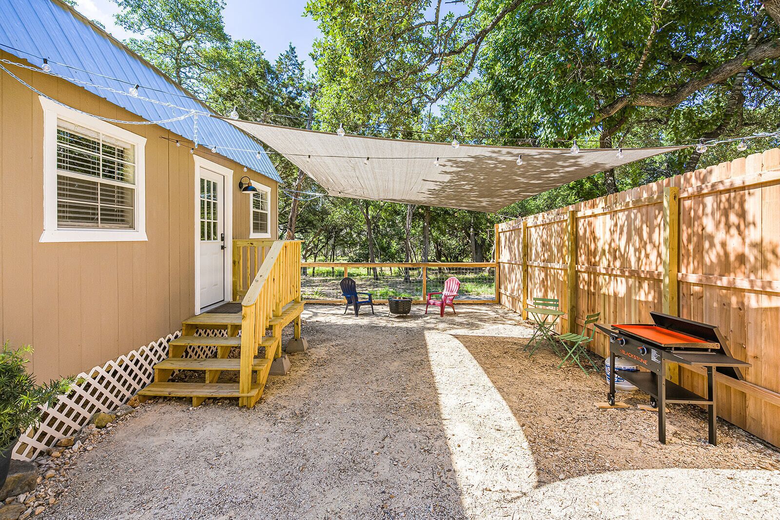 Un espace extérieur abrité comprenant un barbecue, une terrasse en bois et des sièges.
