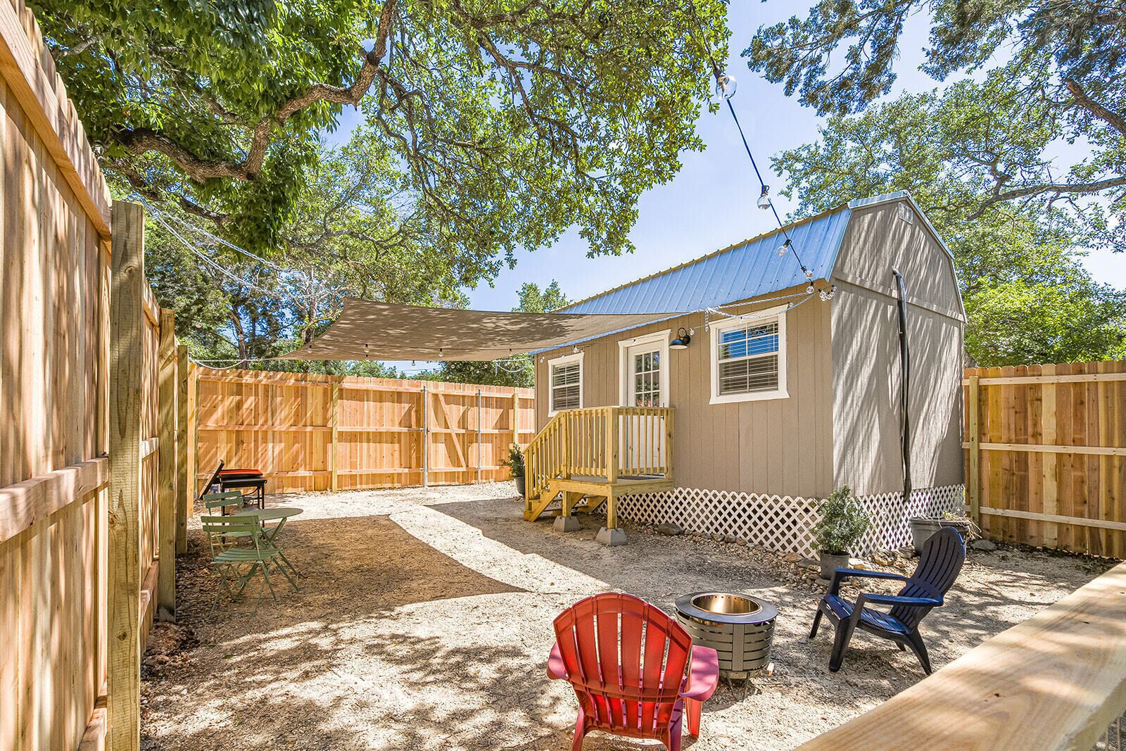 Un jardin avec une terrasse en bois, un patio couvert et un petit abri de jardin.