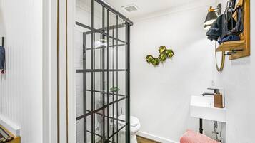 Une salle de bain avec une douche à parois de verre, des toilettes, un lavabo avec un porte-savon en bois et un porte-serviettes sur lequel est posée une serviette.