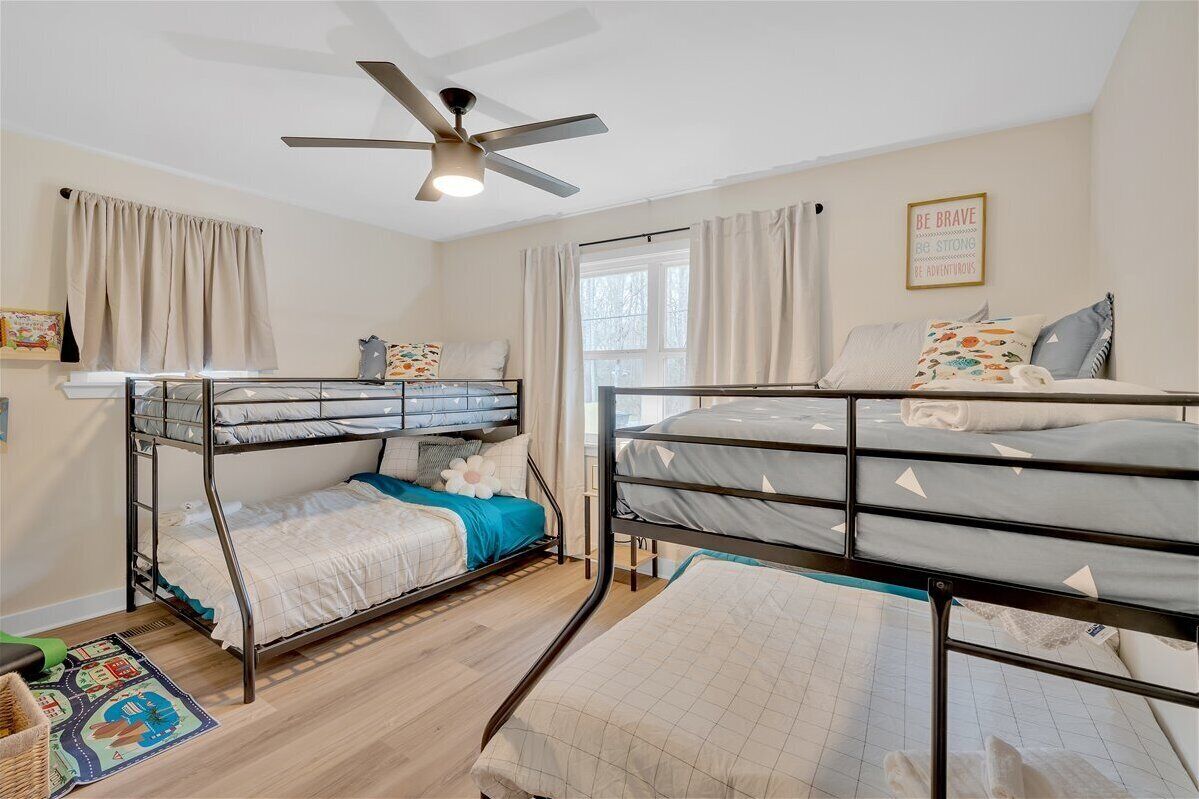 A dormitory room with bunk beds, a ceiling fan, and a motivational poster on the wall.