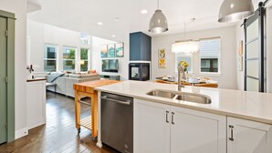 Una cucina moderna con lavastoviglie, lavello e illuminazione a sospensione.