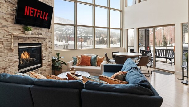A modern living room with a fireplace, a large window, and a flat-screen TV mounted on the wall. - 3min Walk to Ski Lift*Hot Tub*Epic Kids Room*Views (Brian Head)