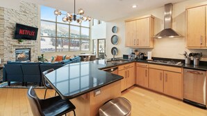 A modern kitchen with a central island, wooden cabinets, and a stone wall. - 3min Walk to Ski Lift*Hot Tub*Epic Kids Room*Views (Brian Head)