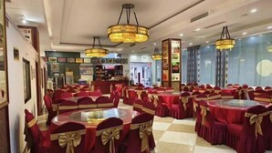 A banquet hall with round tables and chairs, each adorned with red tablecloths and gold sashes. - Hongyan Business Hotel (Baoxing)