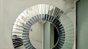 A bathroom with a round mirror, a white sink, and a marble wall. - THE ADDRESS HOTEL AND TOWER (Abuja)