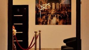 A lobby with a modern light fixture, a framed photograph on the wall, and a red rope barrier. - THE ADDRESS HOTEL AND TOWER (Abuja)