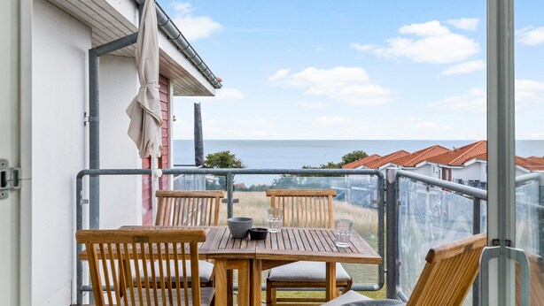 Un balcón con muebles de madera y vista al mar.