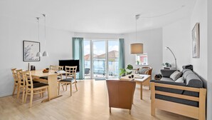 Un apartamento moderno con comedor, sofá, televisor y balcón con vistas a edificios.