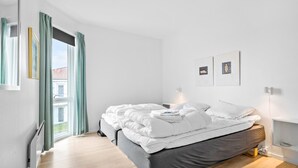 Un dormitorio moderno con una cama grande, una mesita de noche y un ventanal con cortinas.