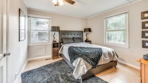 Una camera da letto con un letto, un ventilatore a soffitto, due comodini e una finestra.