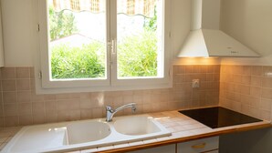 Una cocina con un lavamanos doble, una estufa y una ventana con cortinas.