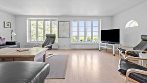 Een ruime woonkamer met een groot raam, een flatscreen televisie en een comfortabele zithoek.