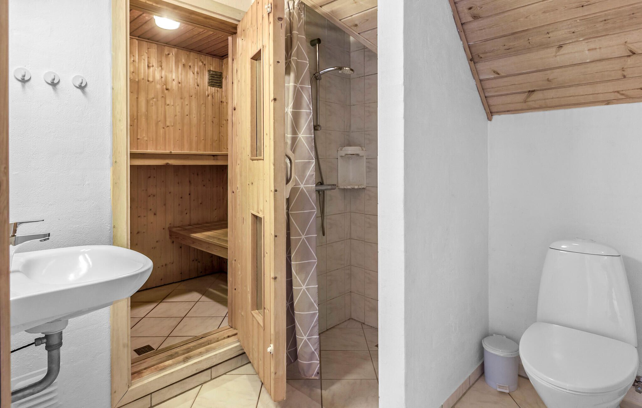 A wooden cabin bathroom with a sink, toilet, and shower.