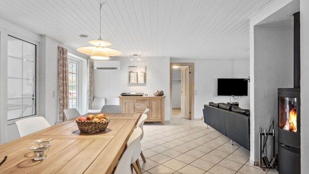 Et moderne køkken med et træspisebord, en pejs og et TV ophængt på væggen.