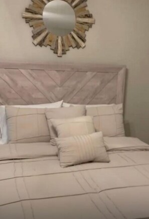 A bed with a headboard, multiple pillows, and a wall-mounted mirror. - Pk’s Residence (Roosevelt)