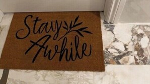 A door with a doormat that reads "Stay Awhile".