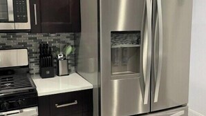 A modern kitchen with dark cabinets, a stainless steel refrigerator, a microwave, and a gas stove.