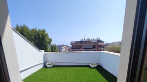 Una azotea con césped artificial verde y paredes blancas.