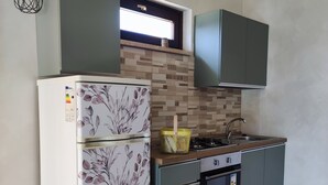 Una cocina con nevera, estufa, pileta y alacenas.