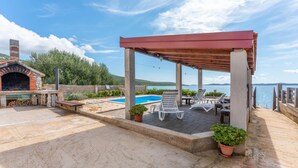 A covered outdoor area with a pool, lounge chairs, and a barbecue. - Gorgeous home in Dobropoljana (Dobropoljana)