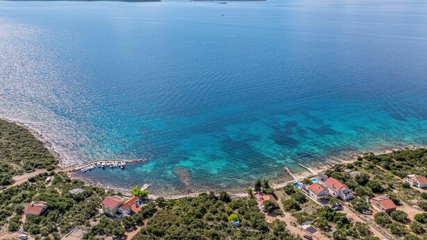 An aerial view of a coastal area with clear blue waters, a marina with boats, and residential buildings with red roofs. - Gorgeous home in Dobropoljana (Dobropoljana)